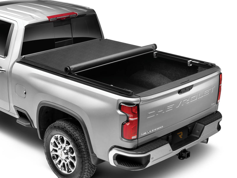 TruXedo TruXport soft roll-up tonneau cover rolled partway toward the cab on a silver pickup, rear three-quarter view