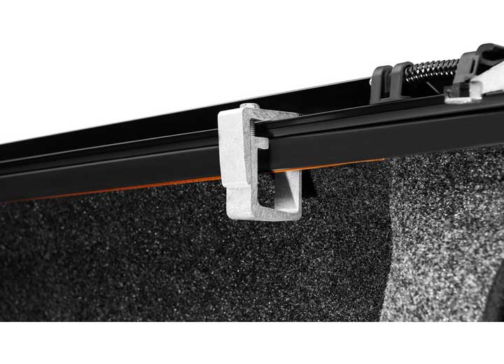Close-up of the bed-rail clamp tightened onto the underside of the side rail on a TruXedo TruXport soft roll-up tonneau cover