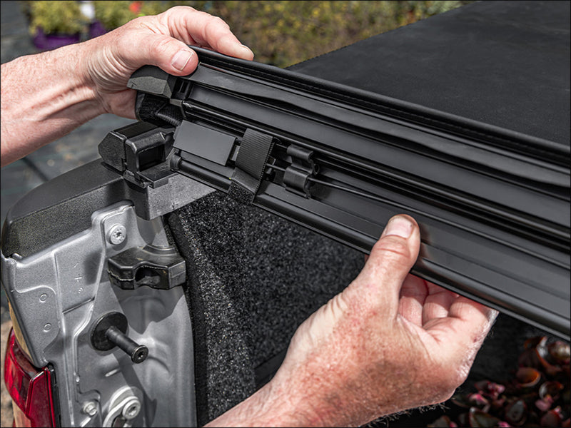 Close-up of the side rail being clipped down onto the bed rail during fitting on a TruXedo TruXport soft roll-up tonneau cover