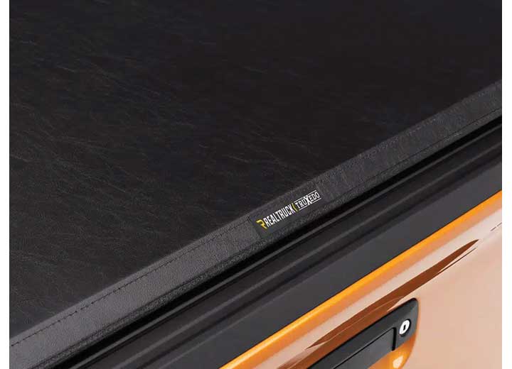 Close-up of the side rail running the length of the bed above an orange bedside on a TruXedo TruXport soft roll-up tonneau cover