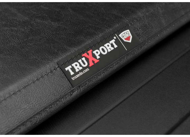 Close-up of the TRUXPORT name plate in tight macro on the cover's rear seam on a TruXedo TruXport soft roll-up tonneau cover