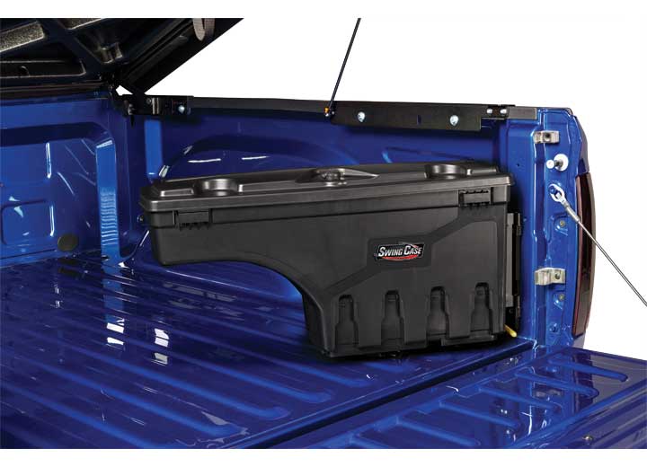 UnderCover SwingCase toolbox stowed against the bed side panel of a blue pickup bed with the lid closed and the release tab at its base