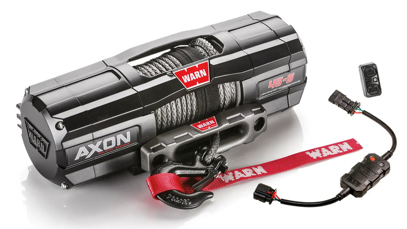 Warn AXON 45-S powersports winch, three-quarter view on white, shown with the rockerbar digital control switch and hub wireless receiver, plus a corded remote socket and wiring harness supplied with it