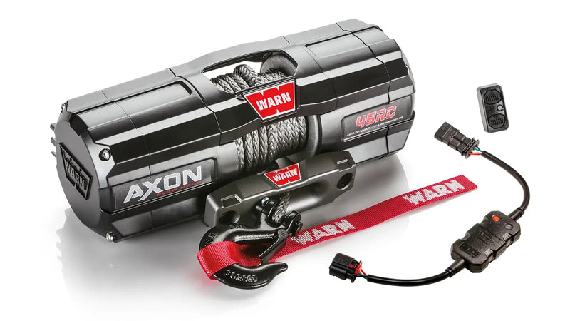Warn AXON 45RC powersports winch, three-quarter view on white, shown with the rockerbar digital control switch and hub wireless receiver, plus a corded remote socket and wiring harness supplied with it