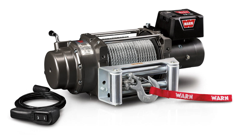 Warn M12 winch, three-quarter view on white, showing the free-spool clutch lever, drum with steel rope, roller fairlead and the wired remote switch