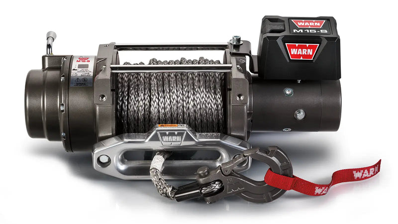 Warn M15-S winch, front elevation on white, showing grey Spydura Pro synthetic rope on the drum, aluminum hawse fairlead, alloy EPIC hook and the control pack badged M15-S
