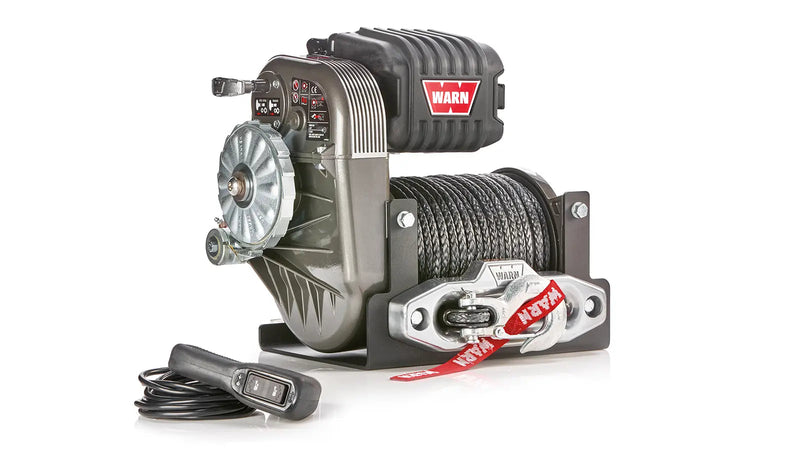 Warn M8274-S winch, three-quarter view on white, showing the free-spool clutch face, gearbox decal panel, control pack and synthetic rope on the drum