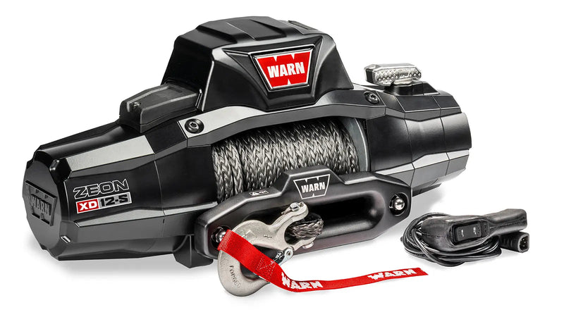 Warn ZEON XD 12-S winch at an angle showing the armored control pack, drum and hawse fairlead, with the corded remote alongside