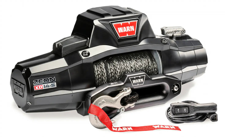 Warn ZEON XD 14-S winch at an angle showing the armored control pack, drum and hawse fairlead, with the corded remote alongside