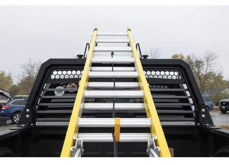 Extension ladder resting on the Weather Guard louvered headache rack, viewed head-on from behind the truck