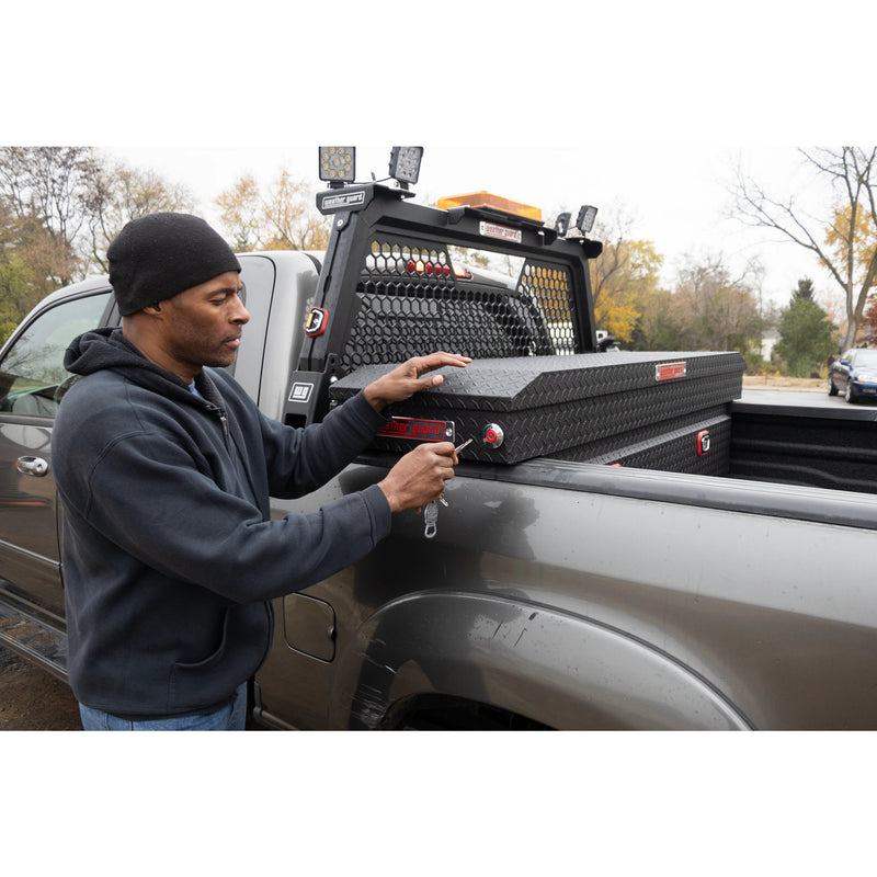 Worker opening a crossover toolbox in a truck bed with the Weather Guard hex headache rack behind
