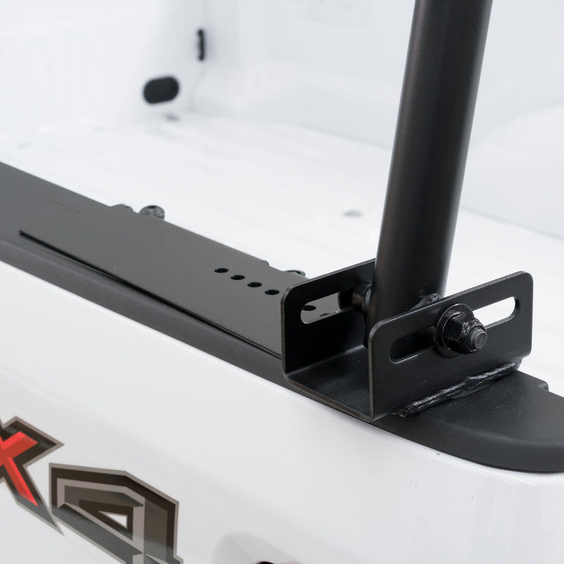 Close-up of a Weather Guard truck rack leg foot clamped to the bed rail of a white pickup with no drilling