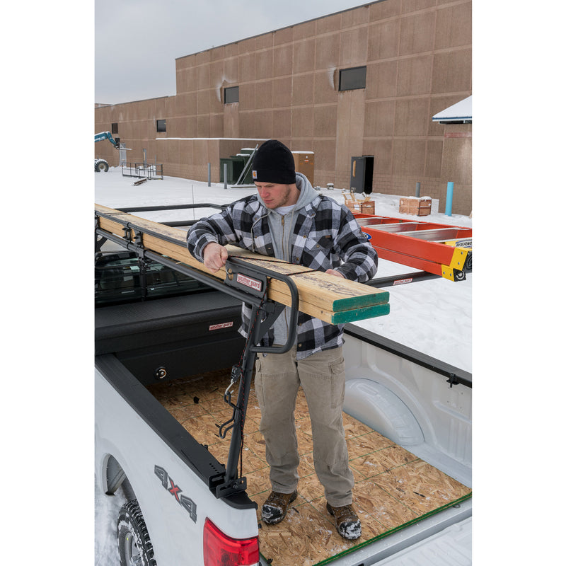 Worker hooking a bungee over a load on a Weather Guard truck rack fitted with an accessory cross member