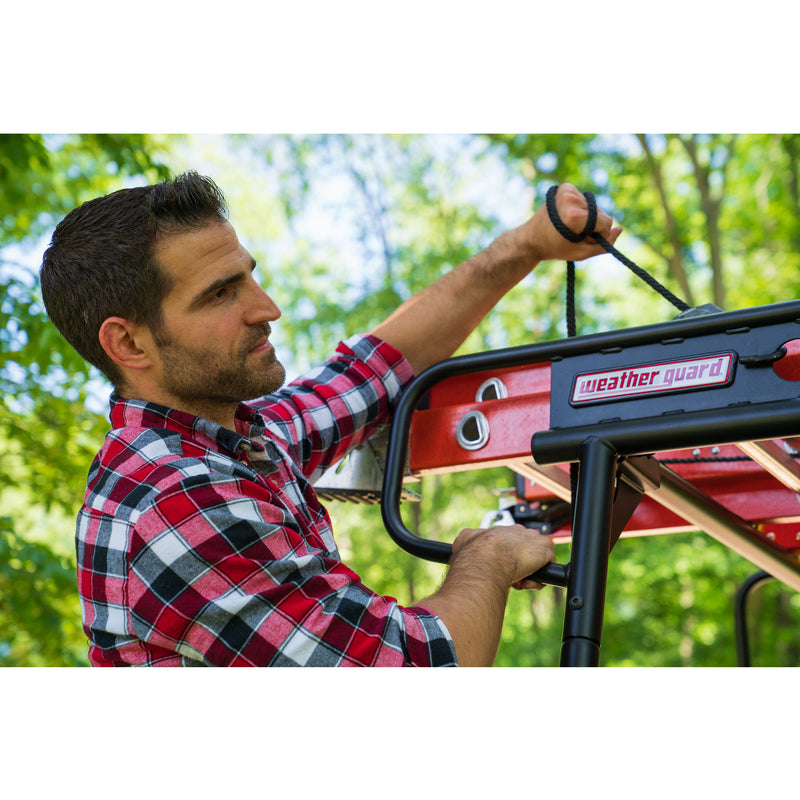 Close-up of a worker hooking a strap into the rear tie-down point on the Weather Guard compact truck rack