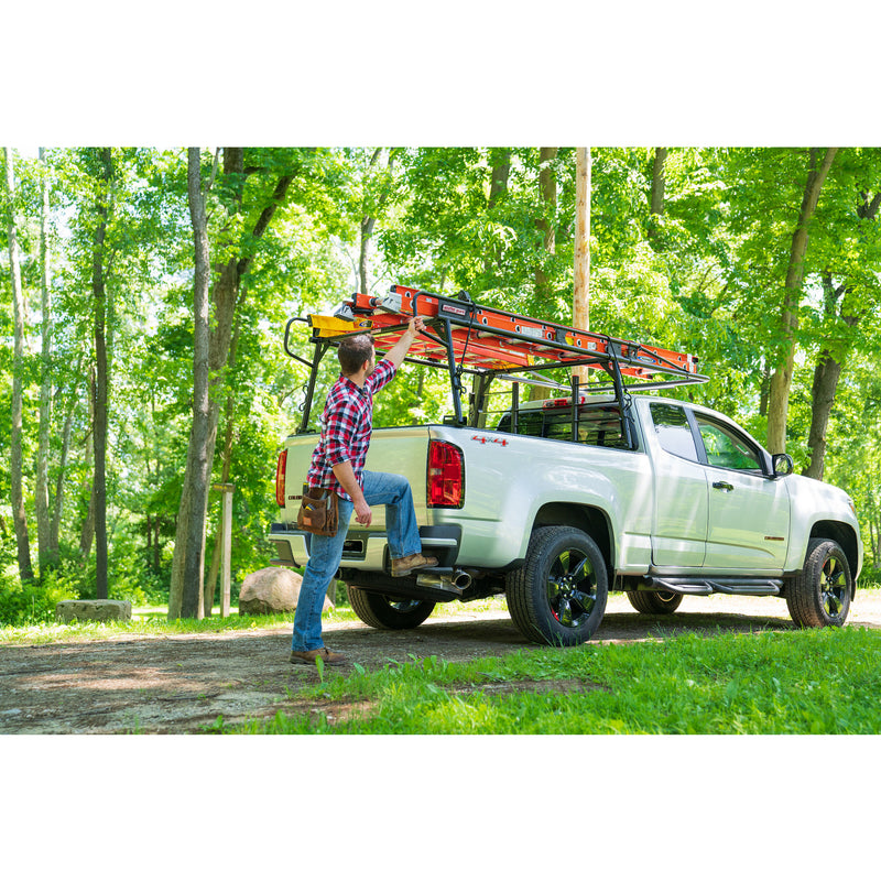 Worker stepping up at the tailgate of a pickup fitted with the Weather Guard compact truck rack and loaded ladders