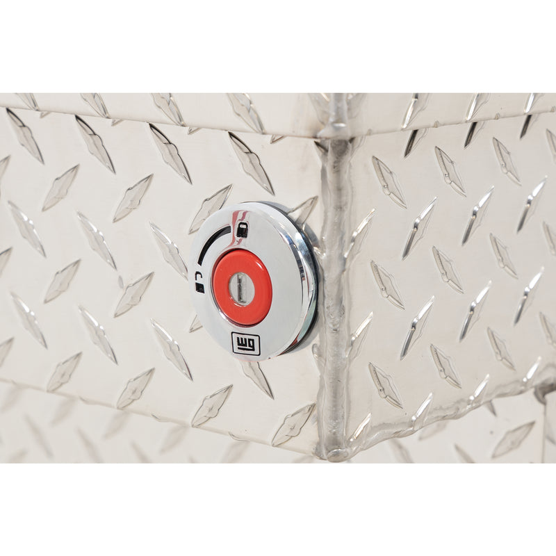 Weather Guard 154-0-04 crossover saddle box in bright aluminum diamond plate, close-up of the red push-button lock and Weather Guard badge