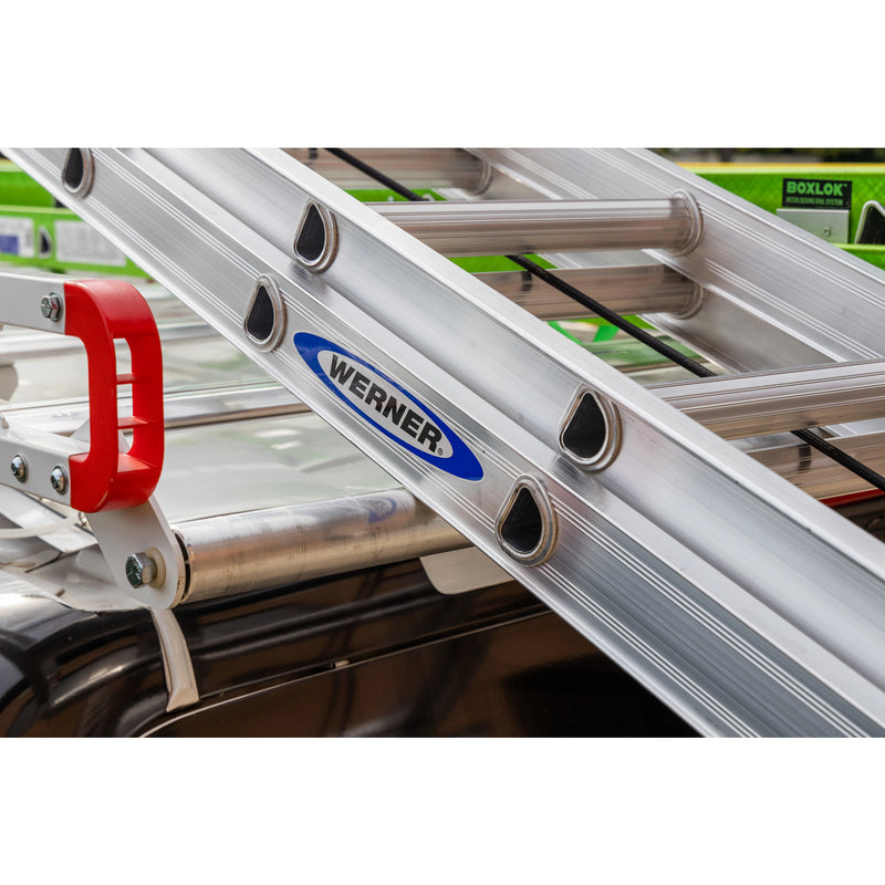 Weather Guard ASRS001 Standard Safari Aluminum Van Roof Rack, close-up of a Werner ladder resting on the rack crossbars behind a red ladder stop