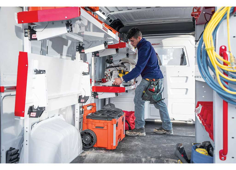 Technician kneeling on the installed Weather Guard rigid floor of a Ford Transit while working with power tools