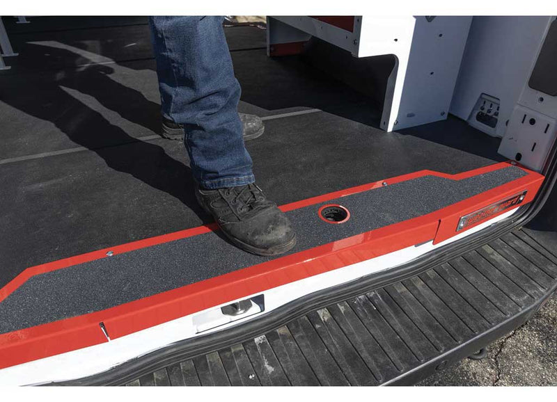 A worker's boot on the Hi-Viz red sill at the rear threshold of a Ford Transit showing the non-slip step