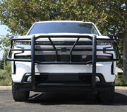 Head-on view of a black Westin HDX grille guard with mesh insert fitted to a white Chevrolet Silverado pickup parked outdoors
