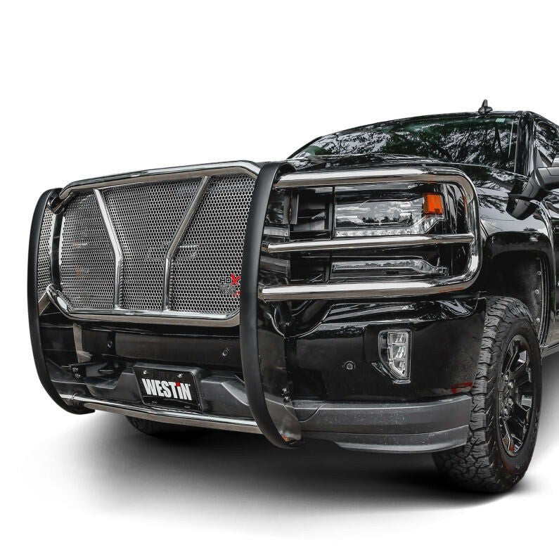 Westin HDX grille guard in polished stainless steel with punch plate mesh mounted on a black pickup truck against a plain white studio background