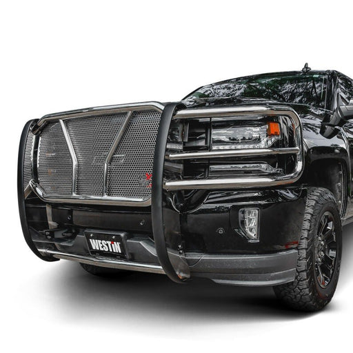 Westin HDX grille guard in polished stainless steel with punch plate mesh mounted on a black pickup truck against a plain white studio background