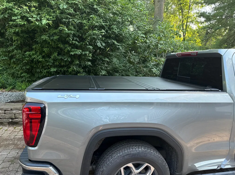Worksport NEXUS hard folding tonneau cover shown on a 2019+ GMC Sierra 1500, a newer generation than the trucks this listing fits: closed hard trifold cover on a silver GMC Sierra, side view