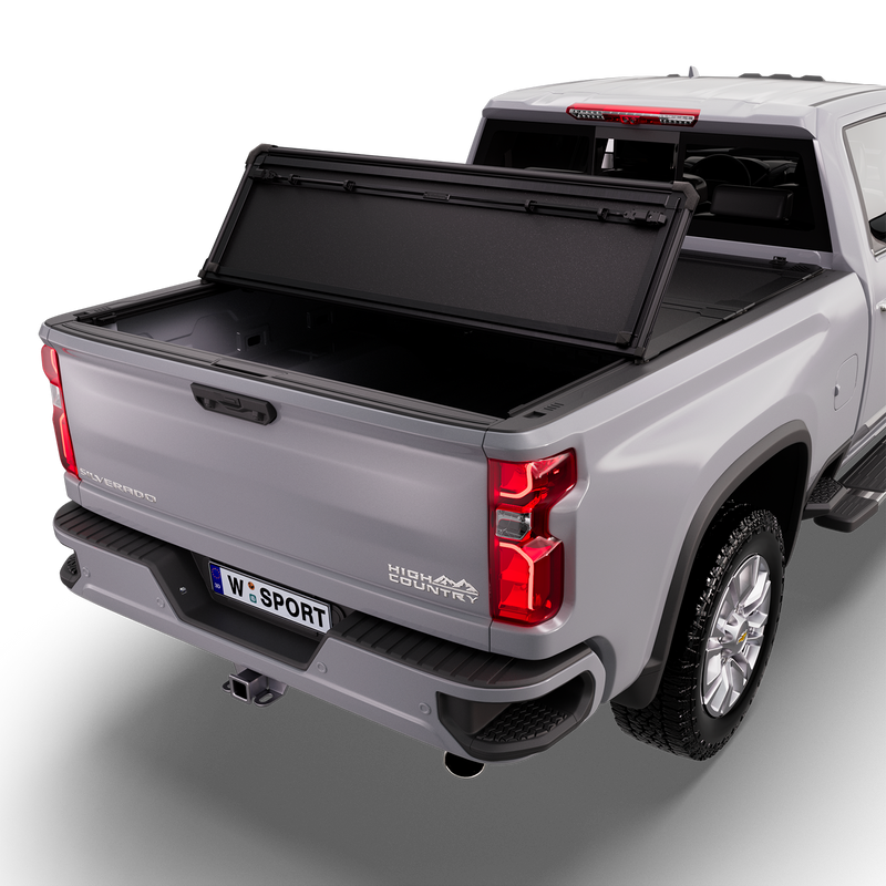 Worksport NEXUS hard folding tonneau cover on a pickup: studio render of a silver Chevrolet Silverado High Country from the rear quarter with a black NEXUS hard folding tonneau cover with the rear panel folded forward