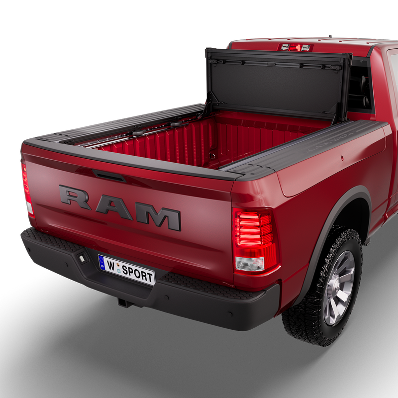 Worksport NEXUS hard folding tonneau cover (With RamBox option) on a pickup: 3D studio render of a red Ram 1500 from the rear quarter with a black NEXUS hard folding tonneau cover folded stack flipped up vertical against the cab, full bed open