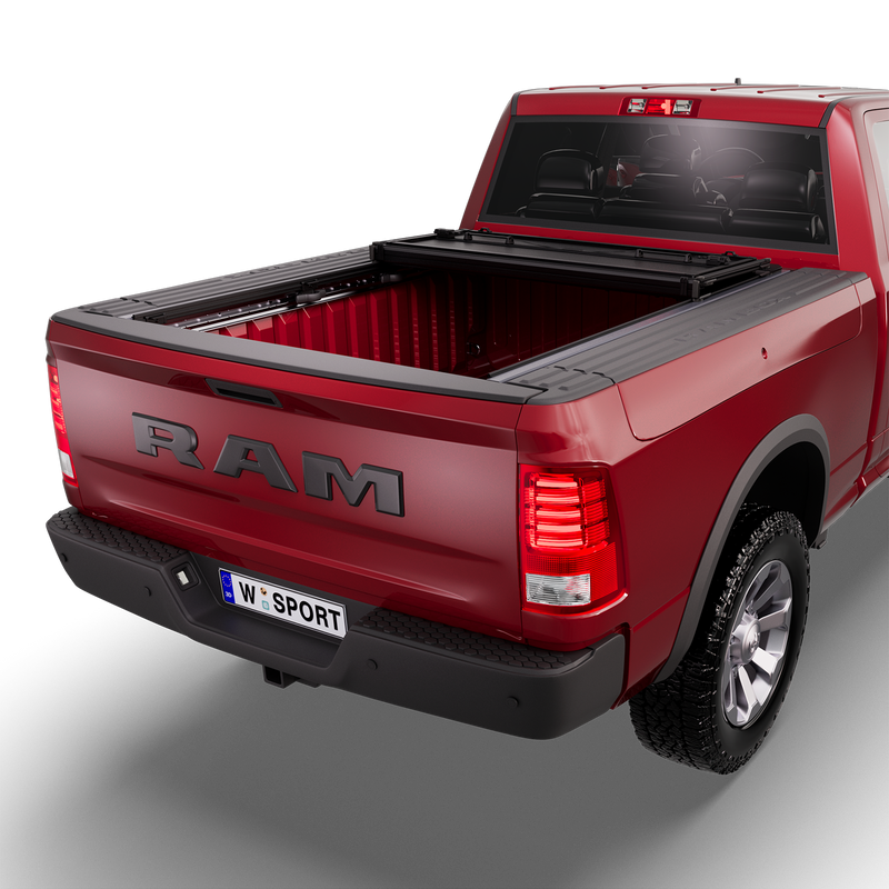 Worksport NEXUS hard folding tonneau cover (With RamBox option) on a pickup: 3D studio render of a red Ram 1500 from the rear quarter with a black NEXUS hard folding tonneau cover folded twice into a stack at the cab end, most of the bed open