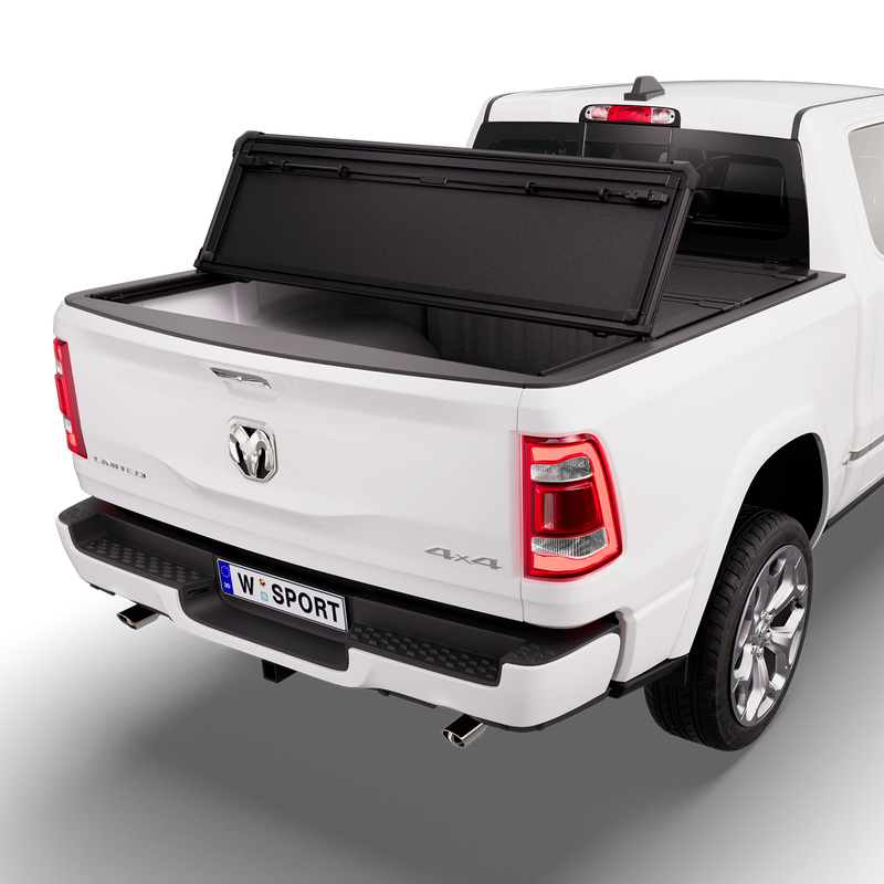 Worksport NEXUS hard folding tonneau cover on a pickup: 3D studio render of a white Ram 1500 from the rear quarter with a black NEXUS hard folding tonneau cover rear panel folded forward, one fold, rear of the bed open