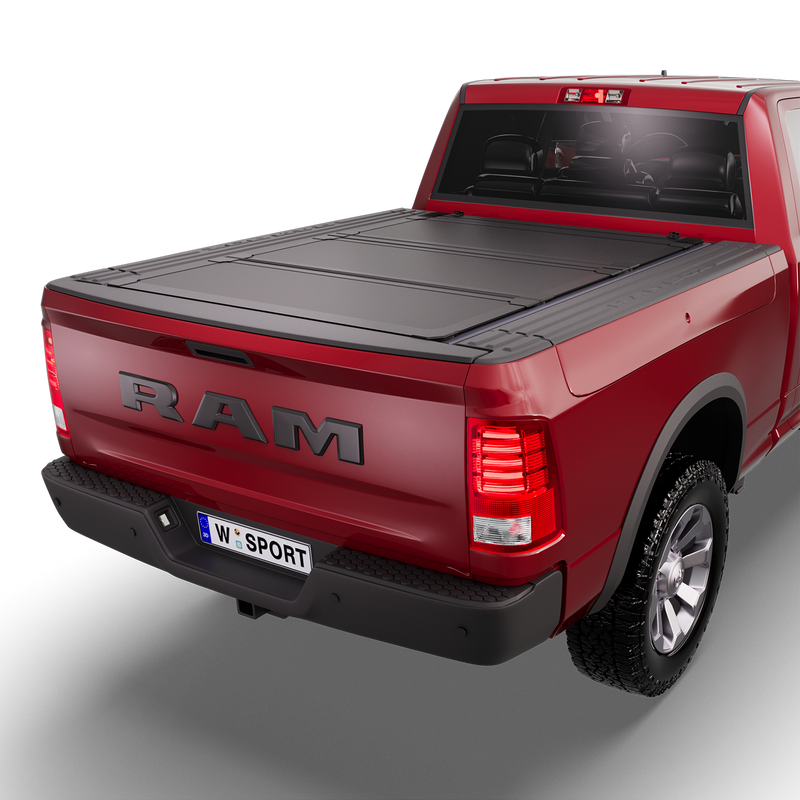 Worksport NEXUS hard folding tonneau cover on a pickup: 3D studio render of a red Ram 1500 from the rear quarter with a black NEXUS hard folding tonneau cover closed, all three panels flat over the bed