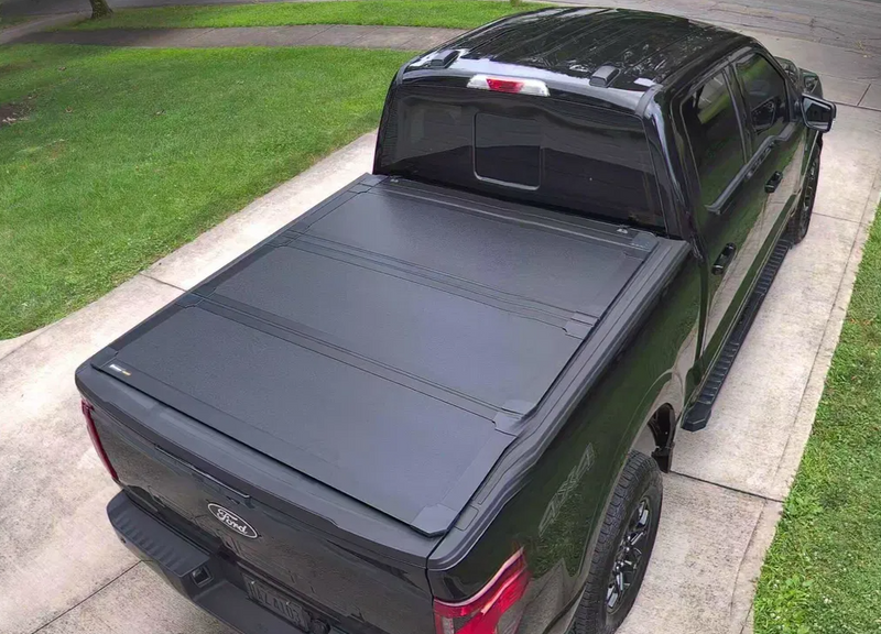 Worksport NEXUS hard folding tonneau cover shown on a 2024+ Ford F-150, a newer generation than the trucks this listing fits: closed hard trifold cover on a black F-150, overhead
