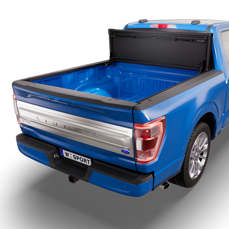 Worksport NEXUS hard folding tonneau cover on a pickup: 3D studio render of a blue Ford F-150 from the rear quarter with a black NEXUS hard folding tonneau cover folded stack flipped up vertical against the cab, full bed open