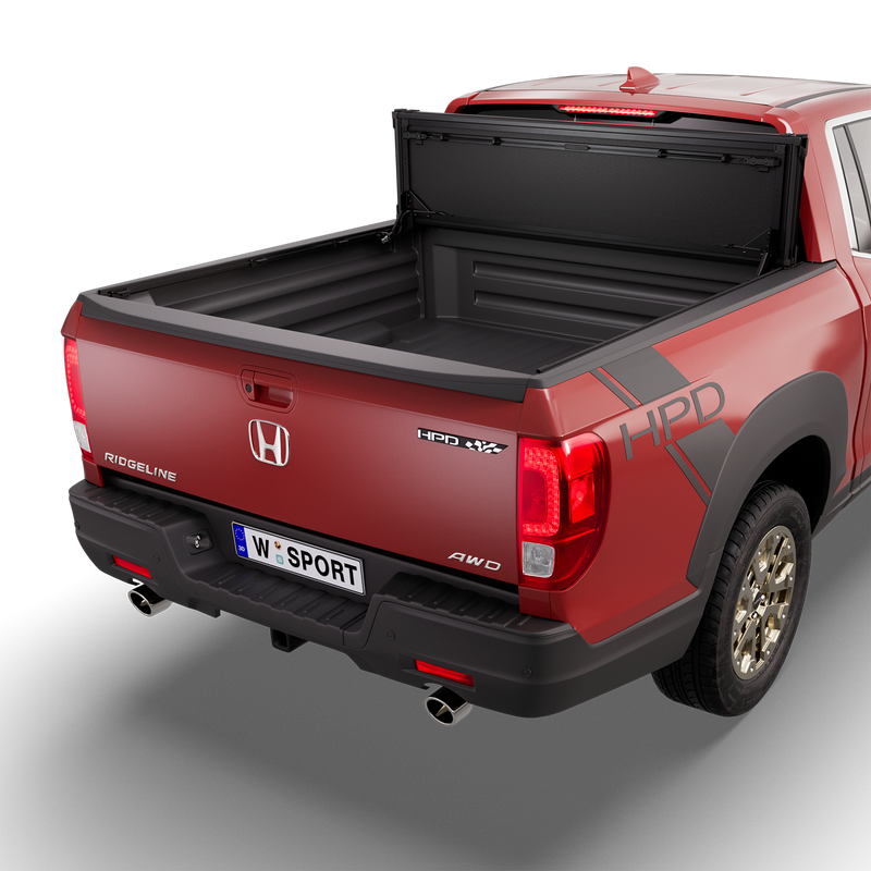 Worksport NEXUS hard folding tonneau cover on a pickup: 3D studio render of a red Honda Ridgeline from the rear quarter with a black NEXUS hard folding tonneau cover folded stack flipped up vertical against the cab, full bed open