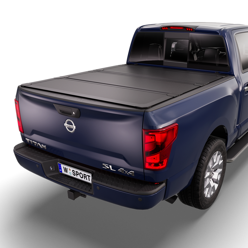 Worksport NEXUS hard folding tonneau cover on a pickup: studio render of a dark blue Nissan Titan SL 4x4 from the rear quarter with a black NEXUS hard folding tonneau cover closed