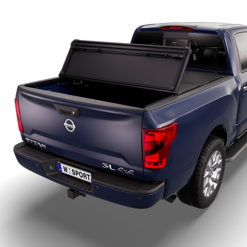 Worksport NEXUS hard folding tonneau cover on a pickup: studio render of a dark blue Nissan Titan SL 4x4 from the rear quarter with a black NEXUS hard folding tonneau cover with the rear panel folded forward