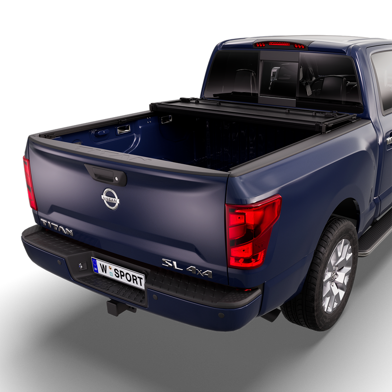 Worksport NEXUS hard folding tonneau cover on a pickup: studio render of a dark blue Nissan Titan SL 4x4 from the rear quarter with a black NEXUS hard folding tonneau cover folded twice and stacked at the cab