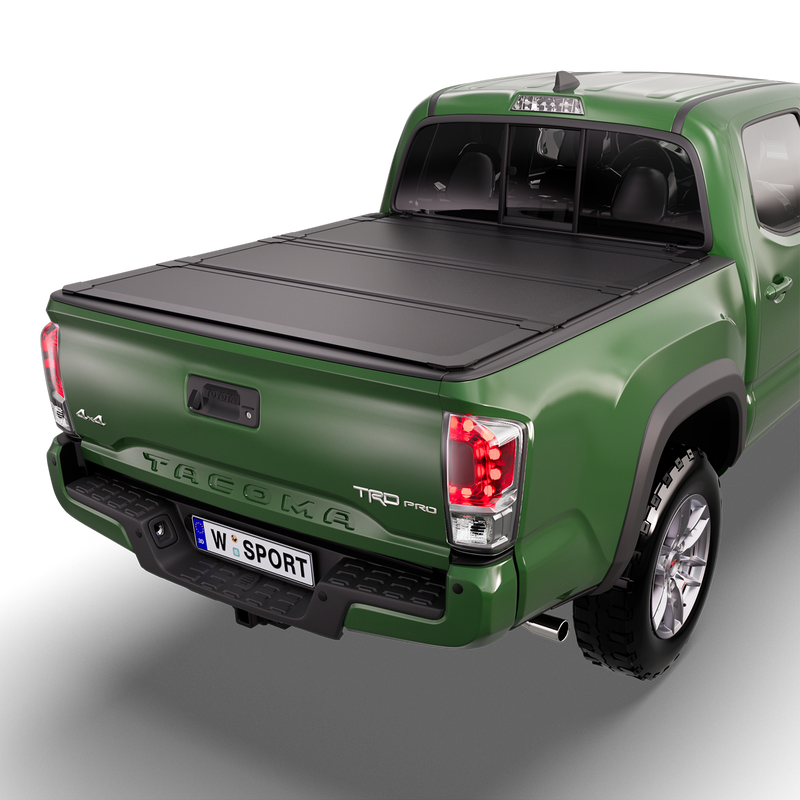 Worksport NEXUS hard folding tonneau cover on a pickup: studio render of a green third-generation Toyota Tacoma TRD Pro from the rear quarter with a black NEXUS hard folding tonneau cover closed