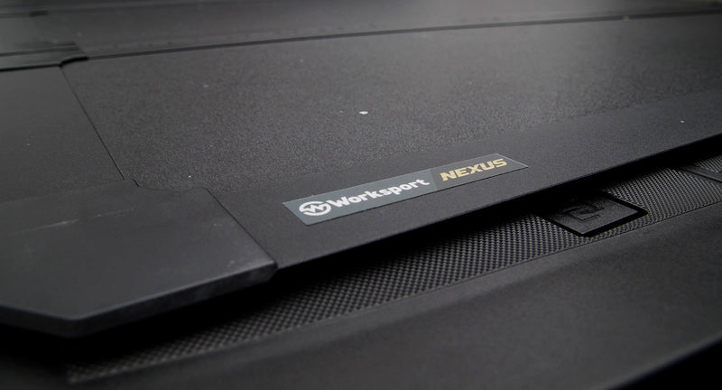 Close-up of the Worksport NEXUS hard folding tonneau cover: close-up of the black textured cover surface showing the Worksport NEXUS badge and panel seam