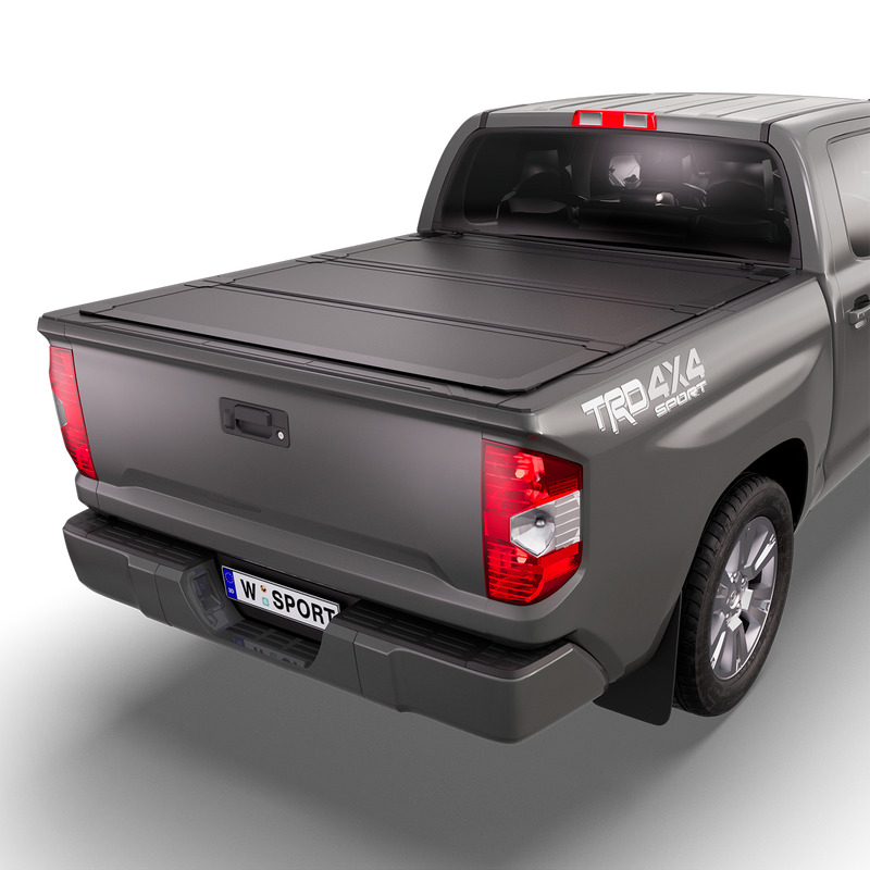 Worksport NEXUS hard folding tonneau cover on a pickup: studio render of a gray Toyota Tundra with TRD 4x4 Sport decals from the rear quarter with a black NEXUS hard folding tonneau cover closed